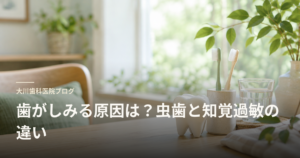 Okawa Dental Clinic blog banner featuring a tooth model and toothbrushes on a wooden table, with the title about causes of tooth sensitivity and the difference between cavities and dentin hypersensitivity.